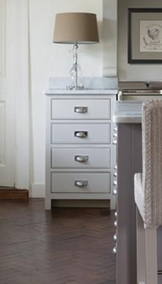 Weißer Schubladenschrank mit moderner Tischlampe im stilvollen Wohnzimmer Weißer Schubladenschrank mit vier Schubladen, darauf eine Tischlampe mit beigem Lampenschirm in einem elegant eingerichteten Raum