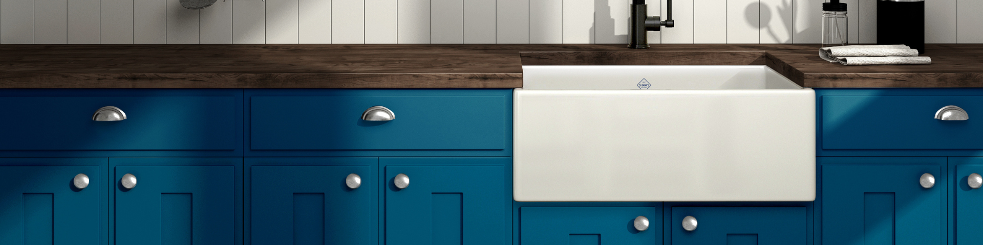 Moderne Landhausküche mit blauen Schränken, Holzarbeitsplatte und weißem Keramik-Spülbecken Küchenzeile mit blauen Unterschränken, dunkler Holzarbeitsplatte und großem weißen Keramik-Spülbecken im Landhausstil