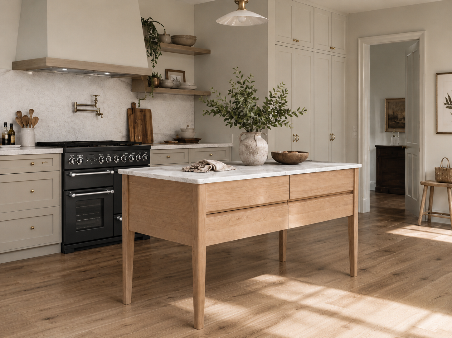 Helle Landhausküche mit Kücheninsel aus Eiche und Marmorplatte, passend zu beigen Shaker-Schränken, schwarzem Range Cooker und Messing-Details – hochwertiges Küchenmöbel für Stauraum und Food-Prep.