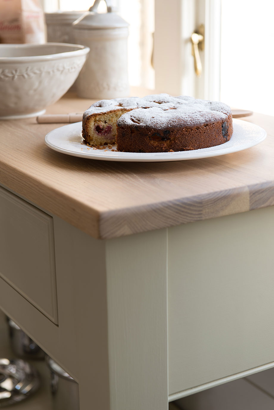 Frischer Kirschkuchen mit Puderzucker auf weißem Teller in gemütlicher Küche Hausgemachter Kuchen mit Kirschen und Puderzucker bestäubt, serviert auf einem weißen Teller auf einer hellen Küchenarbeitsplatte