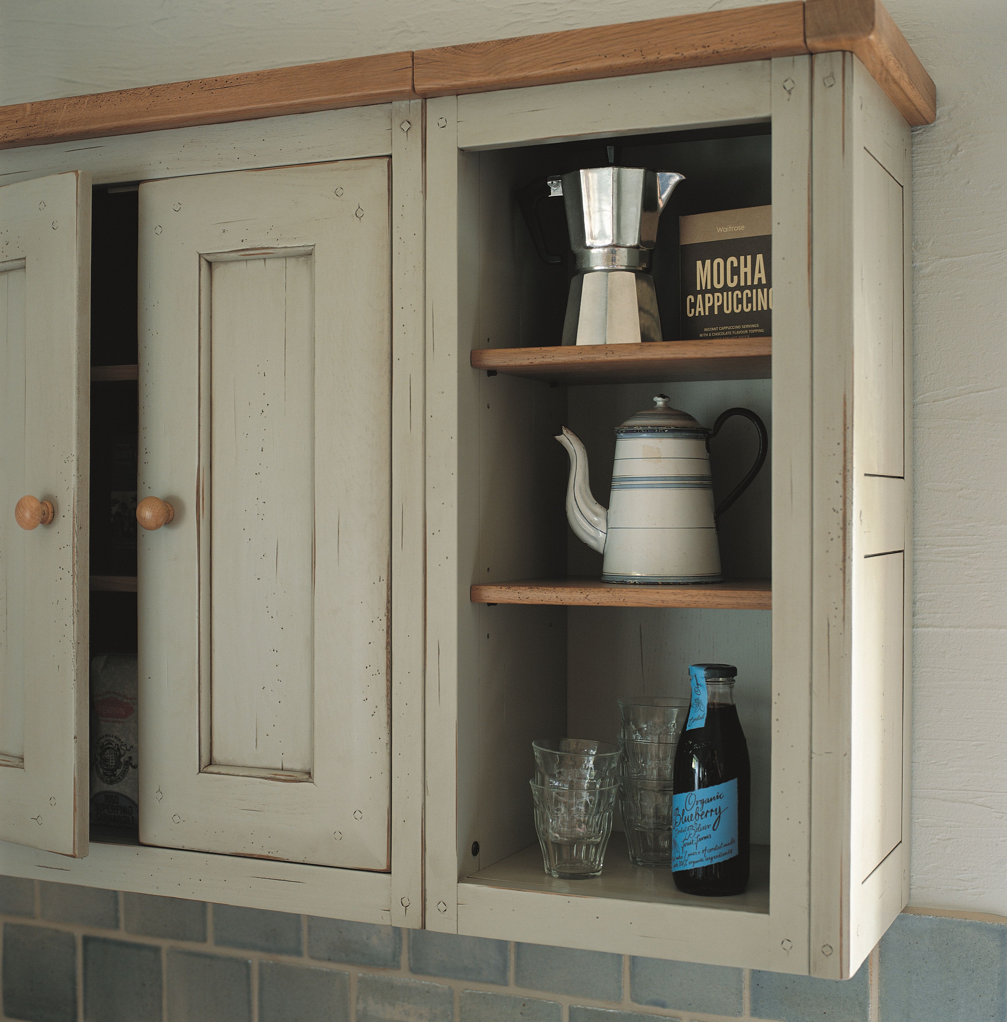 Cremefarbener Landhaus-Küchenhängeschrank aus Holz mit offener Nische, bestückt mit Espressokocher, Emaillekanne, Gläsern und Flasche – Produktfoto Aufbewahrungsschrank Küche