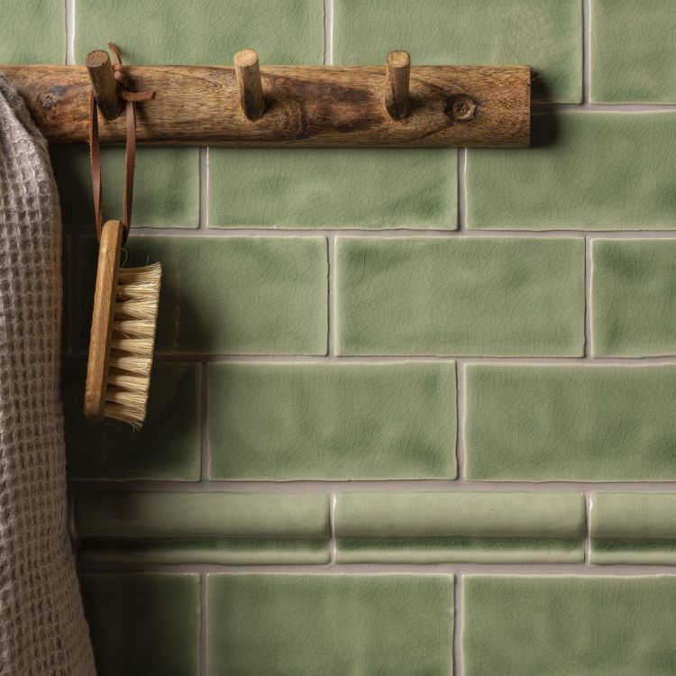 Grüne Metrofliesen, Handtuch und Bürste an Holzleiste