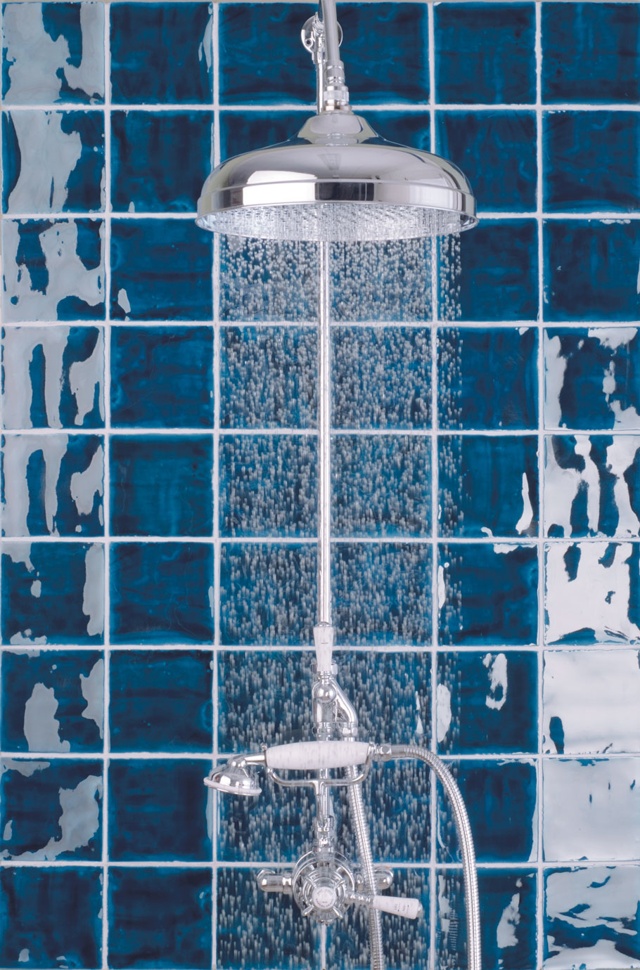 Hochwertige Dusche mit verchromtem Duschkopf vor blauen Fliesen – elegantes Badezimmer-Design Chromfarbene Dusche mit Regenduschkopf, Regenfunktion und edlen blauen Fliesen im Hintergrund