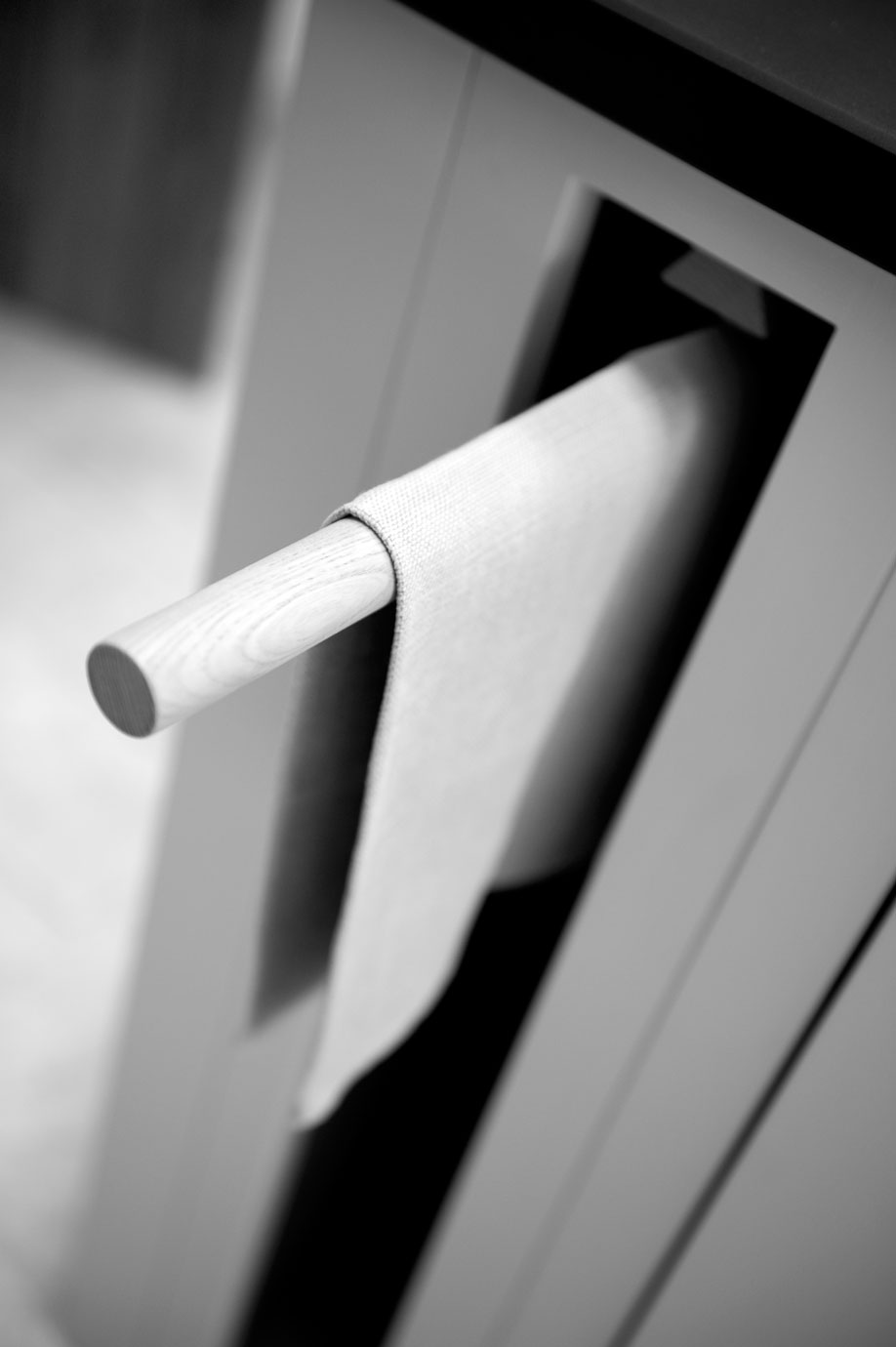 Küchenhandtuchhalter aus Holz mit Handtuch – modernes Küchenzubehör Nahaufnahme eines Holz-Küchenhandtuchhalters mit aufgehängtem Tuch an einer Küchenschranktür