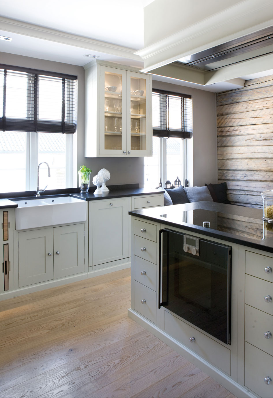 Moderne Landhausküche mit weißen Schränken, Kochinsel und Holzoptik-Wand Helle, moderne Landhausküche mit weißen Schränken, dunkler Arbeitsplatte, großer Kochinsel, eingelassenem Backofen und rustikaler Holzverkleidung an der Wand.